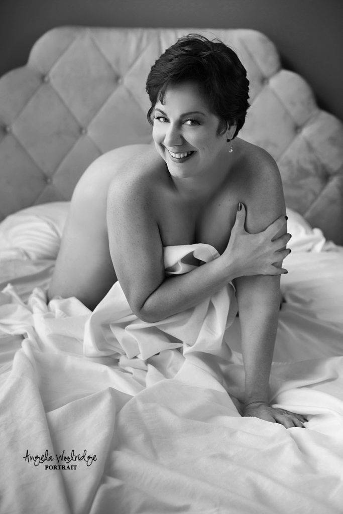Confident woman in white sheets, implied nude