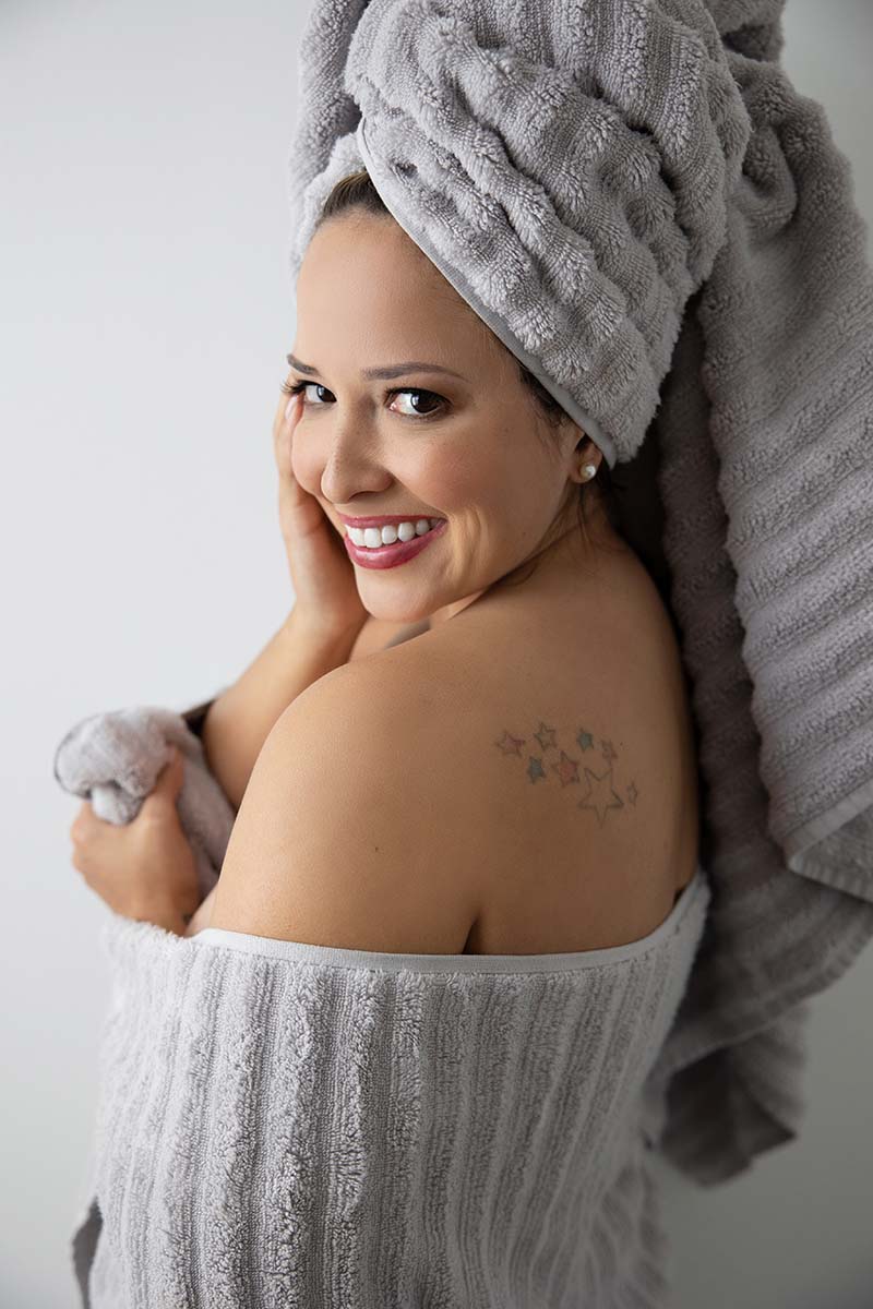 Woman posing in towel for brightly lit boudoir portrait